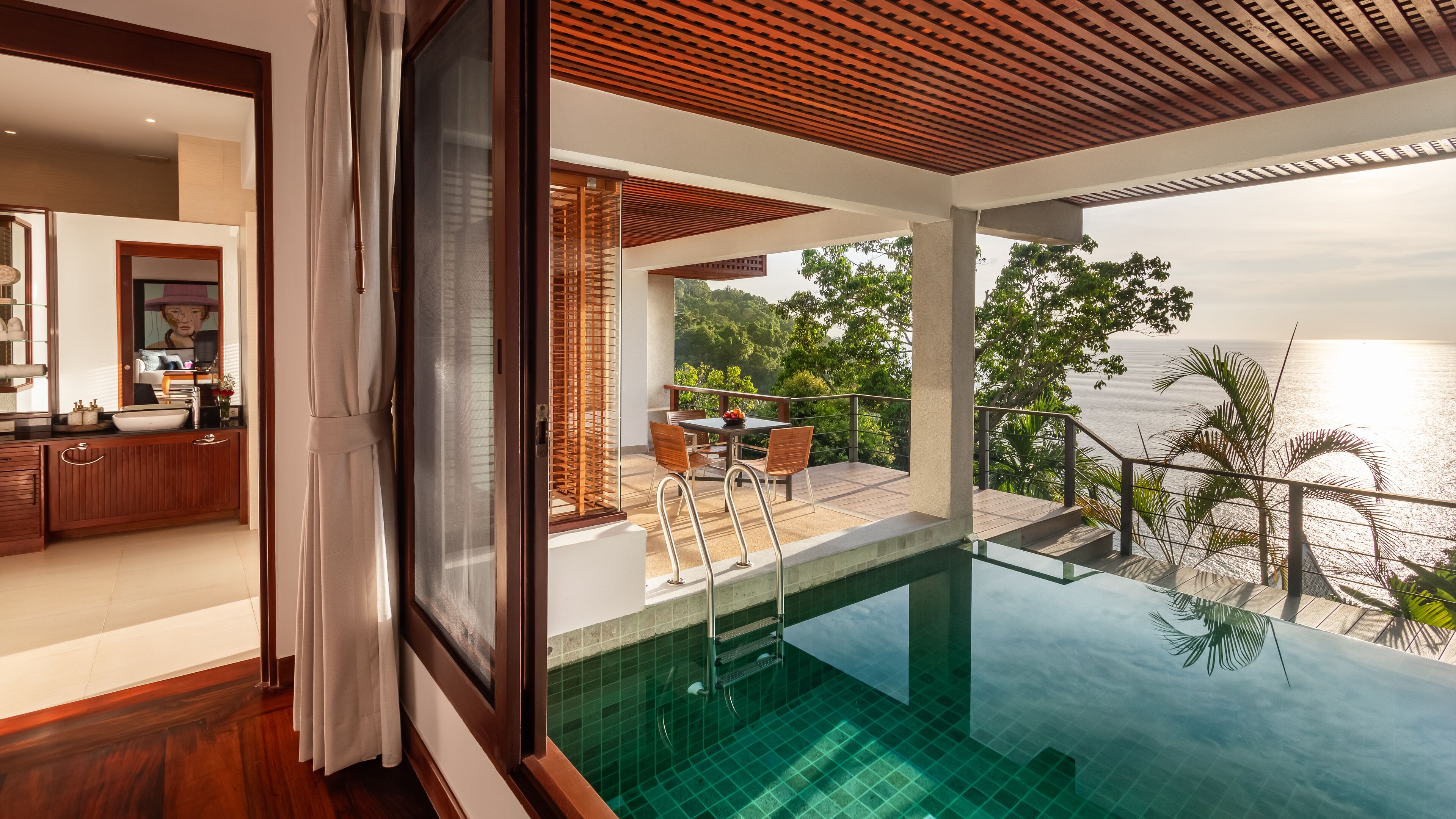 A modern villa with a private pool, a dining area with outdoor seating, and a view of the sea.