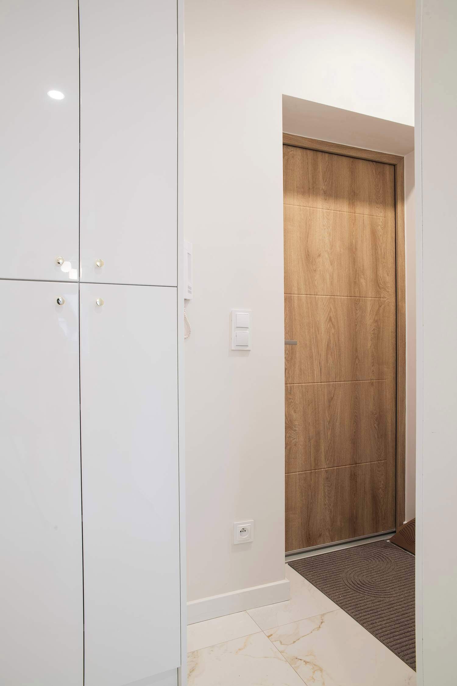 A modern room with a large wardrobe, a wooden door, and a tiled floor.