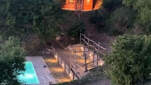 Et hus med swimmingpool og en indhegnet terrassemiljø omgivet af træer.