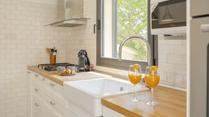 A modern kitchen with white brick backsplash, stainless steel appliances, a large window, and a wooden countertop. - Villa Es Pont de Pedra (Alcúdia)