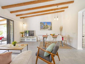 A spacious living area with a dining table, chairs, a sofa, and a TV.
