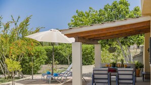An outdoor patio with a pergola, seating, and a table set up for dining. - Villa Es Pont de Pedra (Alcúdia)