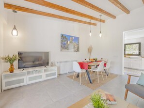 Un salon moderne comprenant un téléviseur, un coin repas et une cuisine.