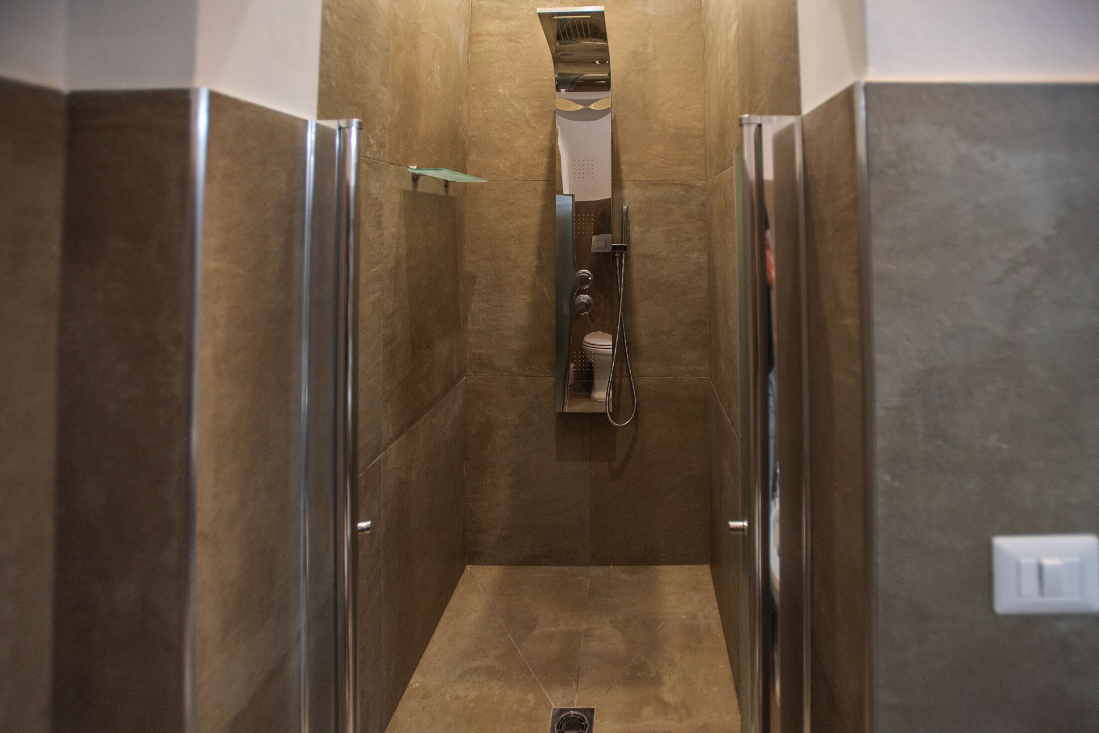 Une cabine de douche moderne dotée d’une porte en verre, d’un pommeau de douche à main et d’un porte-serviettes fixé au mur.