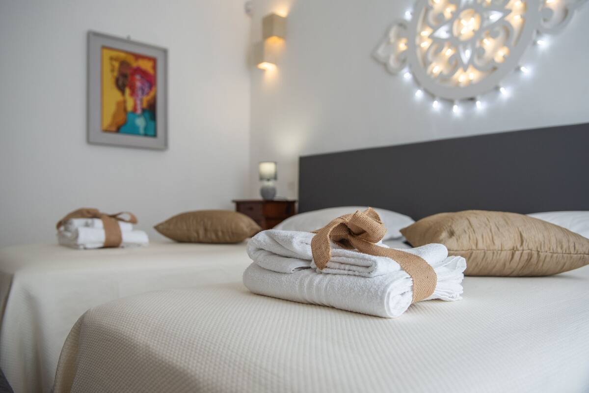 Una cama bien hecha con toallas y un cabecero, un cuadro en la pared y una lámpara decorativa.