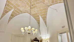 Une pièce dotée d’un plafond voûté, d’un lustre, d’un miroir et de tableaux encadrés accrochés aux murs.