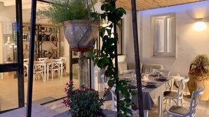Un espace de restauration intérieur avec une table dressée pour deux personnes, entourée de chaises blanches.