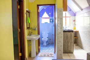 A compact bathroom with a sink, toilet, and shower.