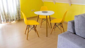 A room with a yellow wall, a round white table, and four yellow chairs. - Charming 1-bed Penthouse in Karen Nairobi (Nairobi)