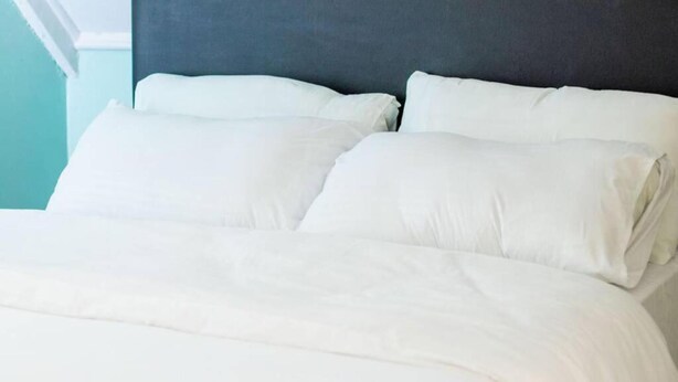 A bed with white bedding and a dark headboard. - Charming 1-bed Penthouse in Karen Nairobi (Nairobi)