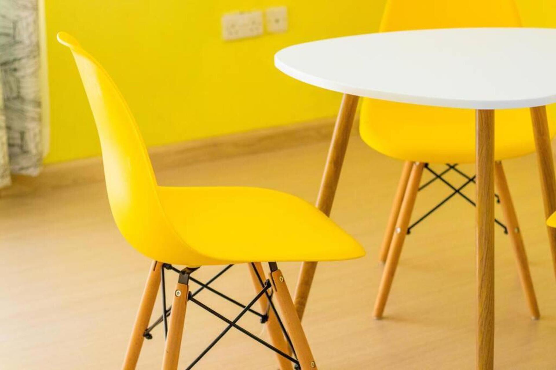 A yellow chair with a white table in a room with yellow walls.