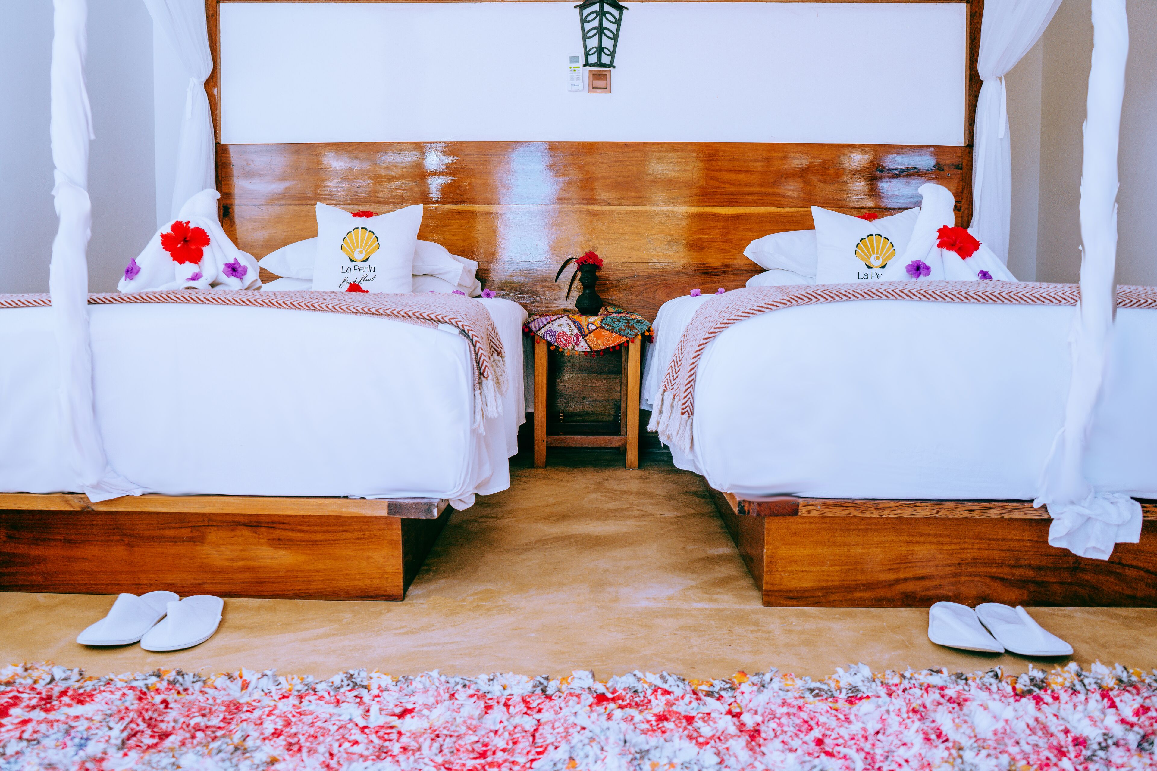 A hotel room with two beds, a nightstand, and a decorative vase.