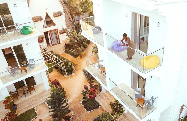 A multi-level hotel with balconies, outdoor seating, and a garden area. - La Perla Beach Resort, Zanzibar - Your Beachfront Private Haven (Pwani Mchangani)