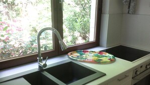 A kitchen with a double sink, a window, and a stove.