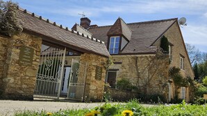 Un bâtiment en pierre à l’architecture traditionnelle, doté d’une entrée fermée par un portail et d’une antenne parabolique.