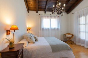 Un dormitorio con cama, mesita de noche, lámpara, silla y candelabro.