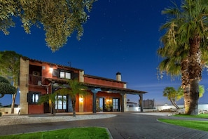 A two-story house with a balcony, a covered patio, and a well-maintained lawn.