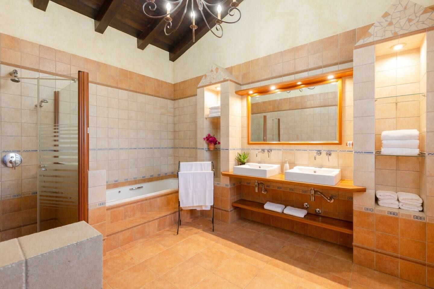 A bathroom with a glass shower enclosure, a double sink vanity, and a large mirror.