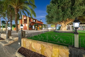 A well-maintained outdoor area with a stone wall, a green lawn, and a large tree.