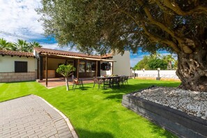 Una casa con patio, comedor y césped bien cuidado.