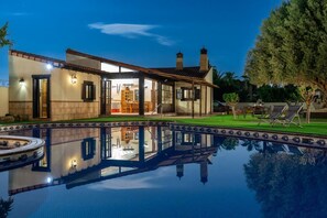 A modern house with a swimming pool, outdoor furniture, and a well-maintained lawn.