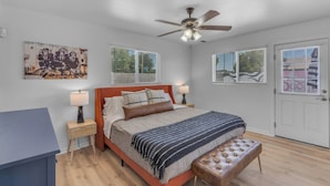 A bedroom with a bed, bedside tables, a ceiling fan, and a door. - Remodeled Gem w/ bocceball - 8 Minutes to Oldtown (Scottsdale)
