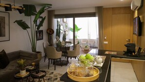 Una sala de estar moderna con comedor, ventanas grandes y cocina equipada con cafetera.