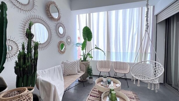 Una sala de estar moderna con un sofá, dos sillones, una mesa de centro y espejos decorativos.