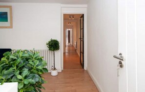 Corridors lead to a door, lined with a potted plant and a radiator.