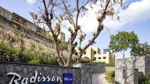 Señal para Radisson Blu Resort Kumbhalgarh, con un muro de piedra y un camino que lleva al edificio.