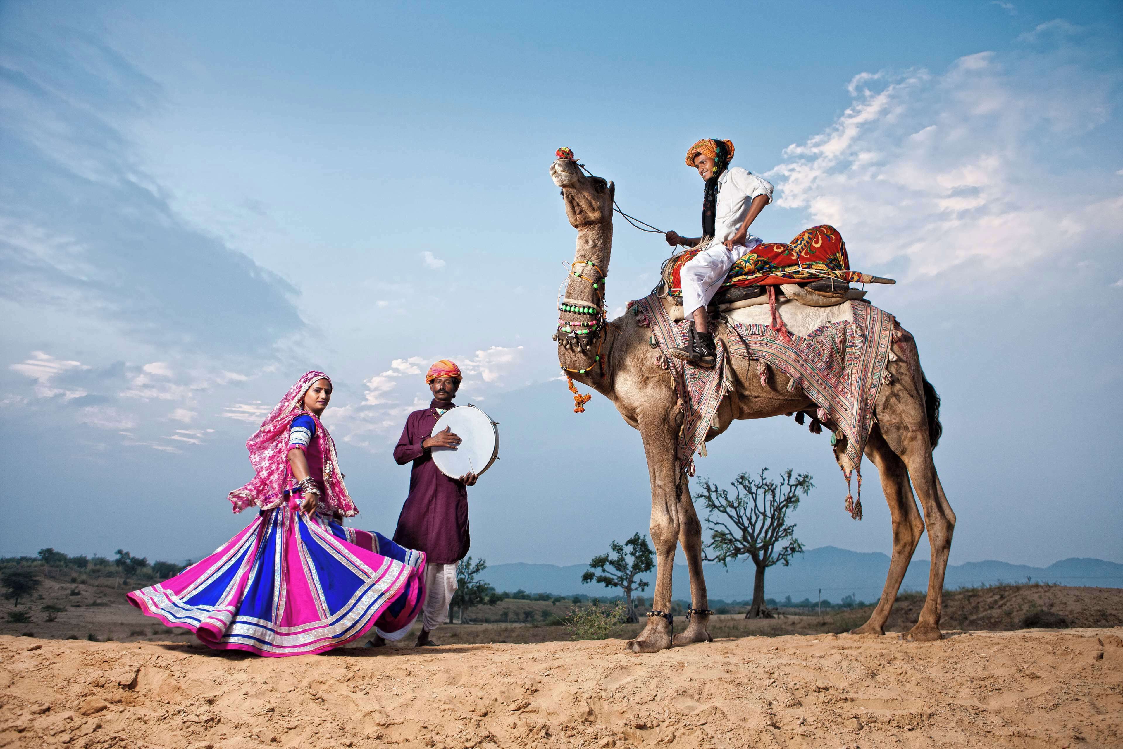 A camel with a rider and a woman in traditional attire.