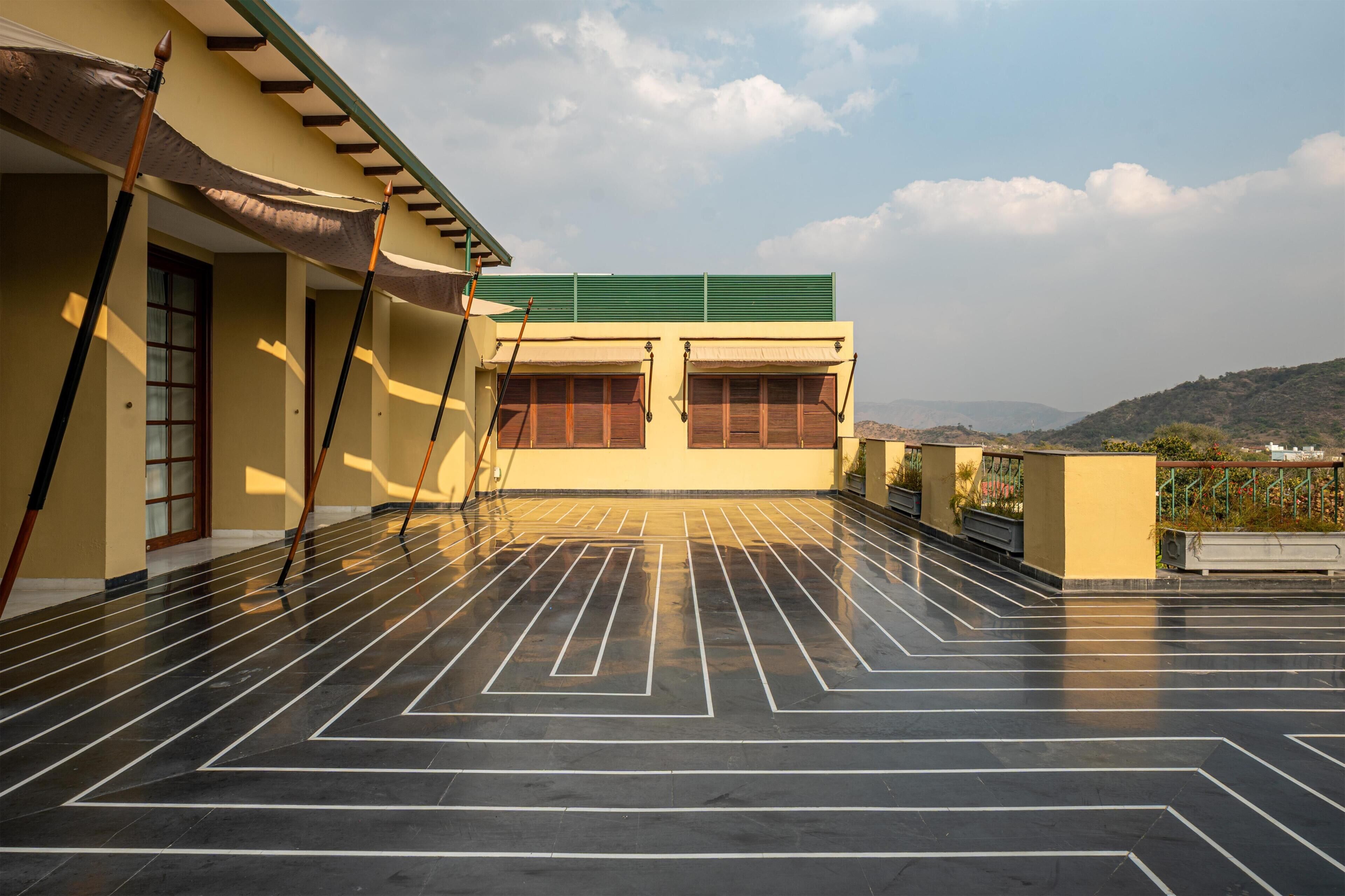 A rooftop terrace with a tiled floor, a green awning, and a building with windows.