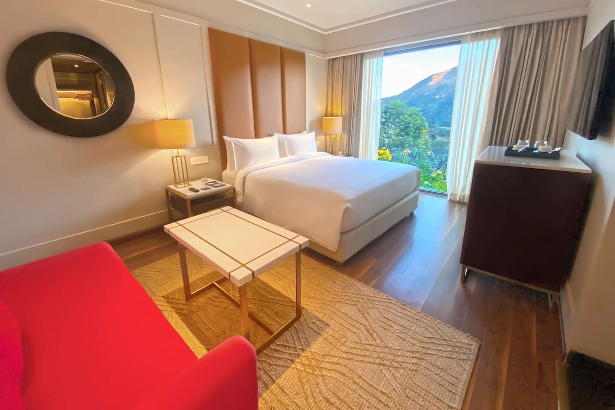 Ein Hotelzimmer mit Bett, Schreibtisch, Stuhl, Fernseher und Blick ins Freie.