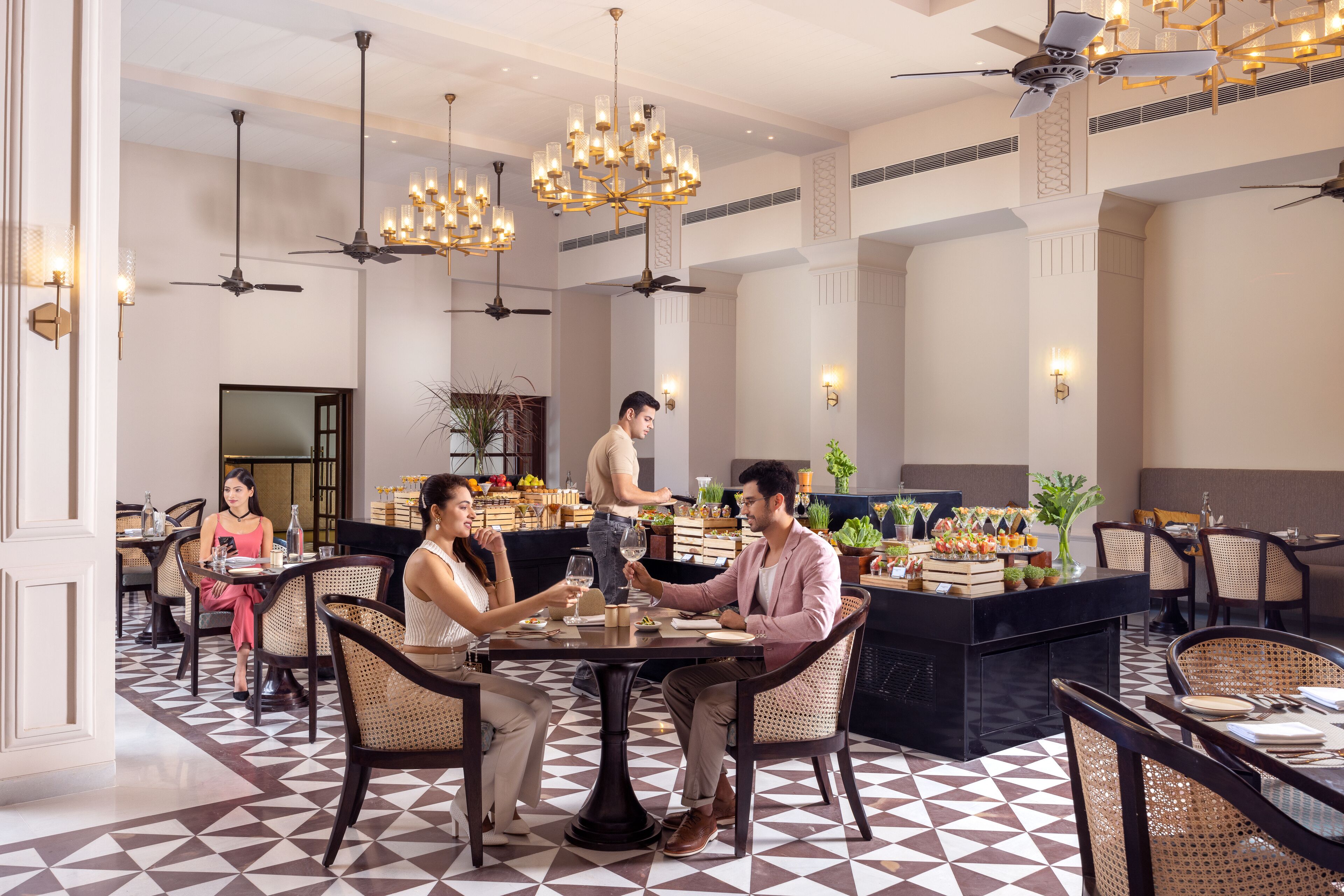 Un restaurante con barra central, varias mesas de comedor, ventiladores de techo e iluminación decorativa.
