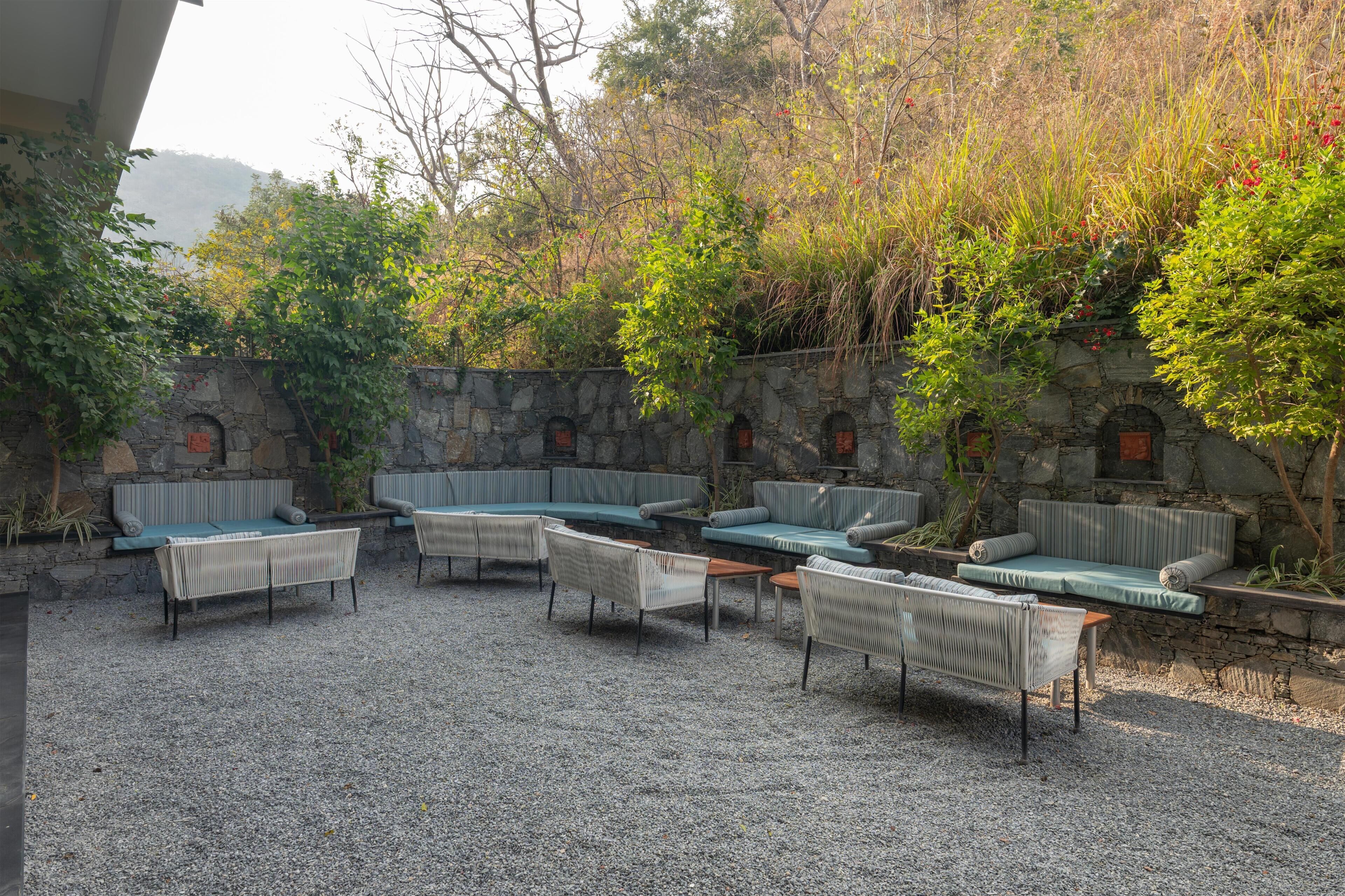 A patio area with seating arrangements and a stone wall backdrop.