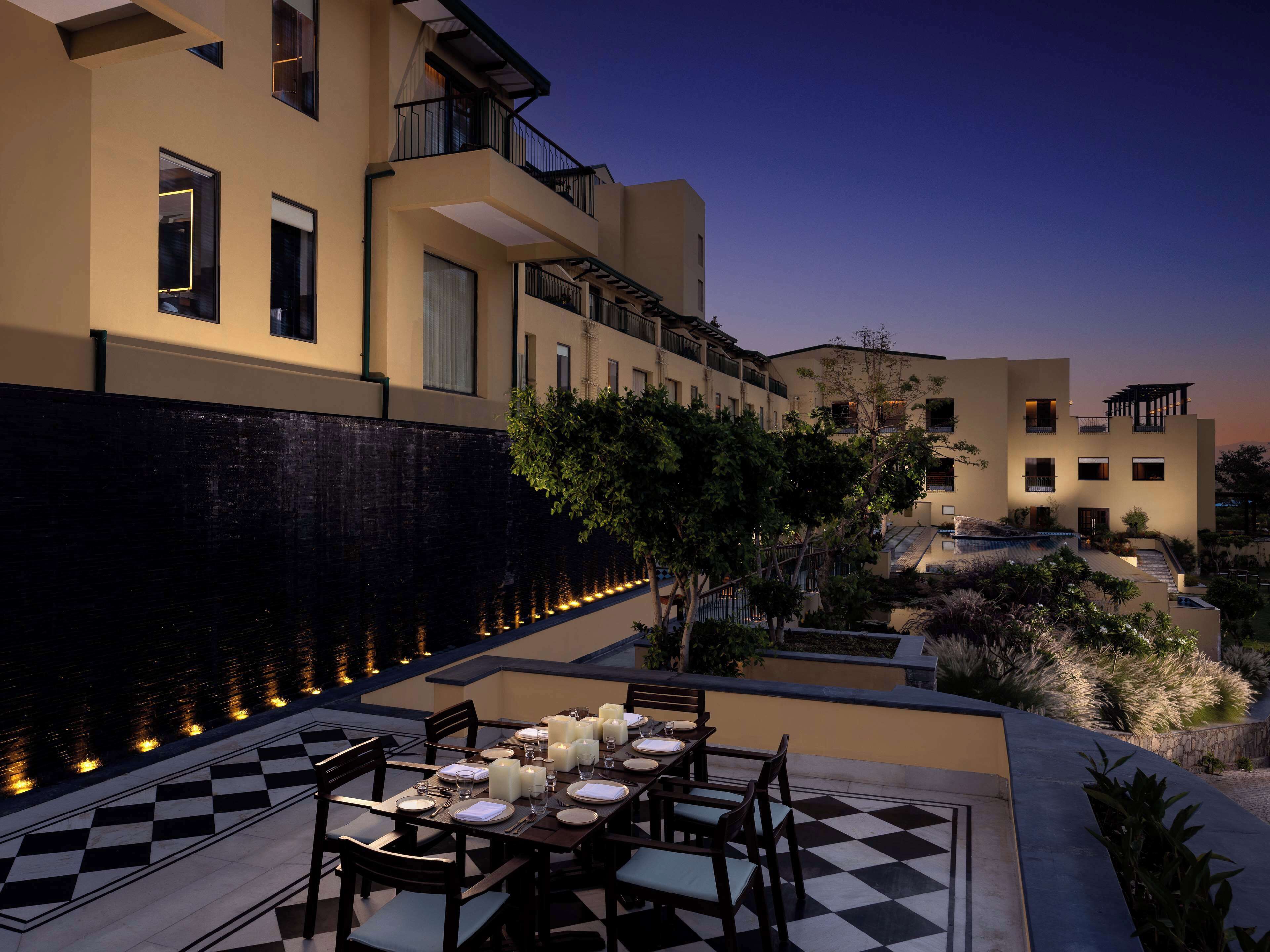 An outdoor dining area with checkered flooring, tables set for dining, and a pool in the background.