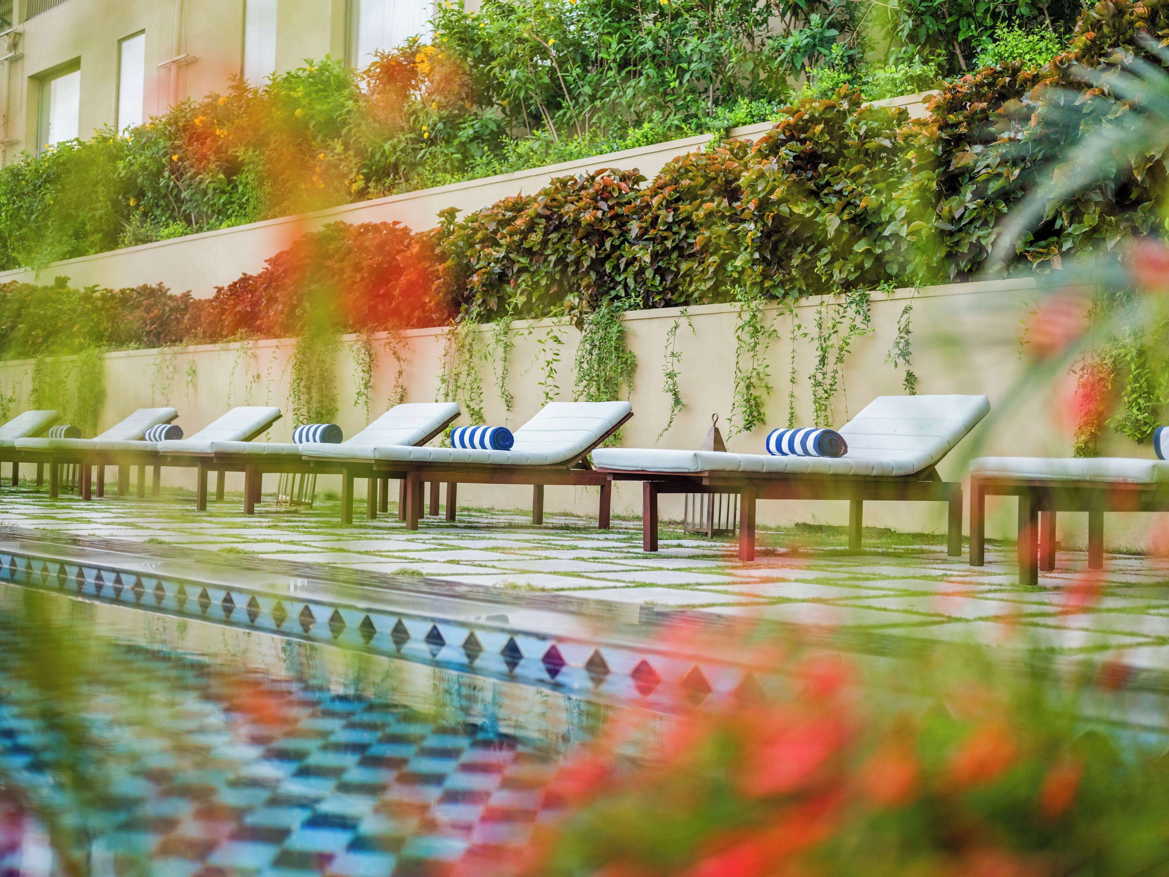 Un área junto a la piscina con sillones de descanso y un solárium con baldosas.