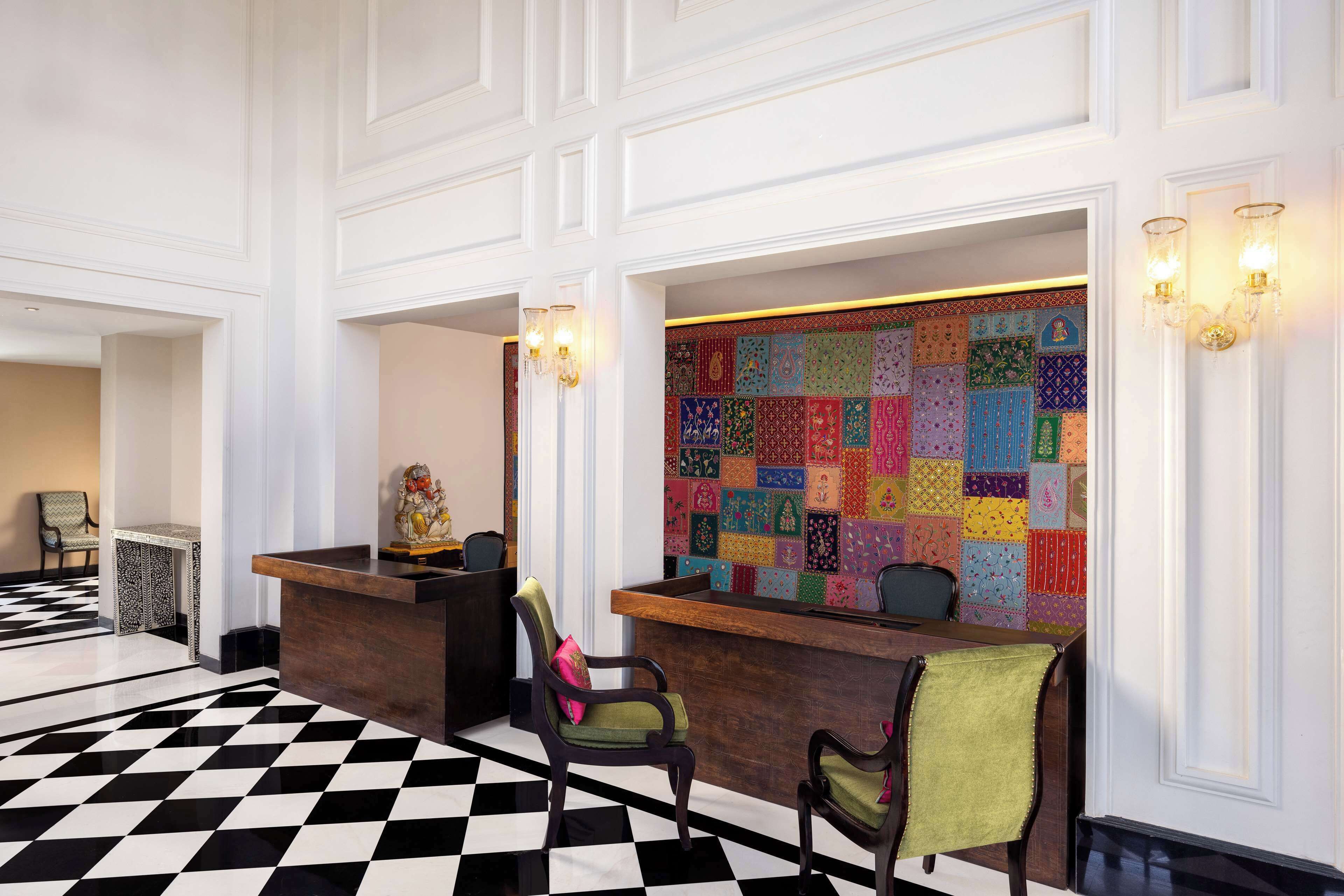 A reception area with a checkered floor, a colorful quilted wall, and a wooden reception desk.