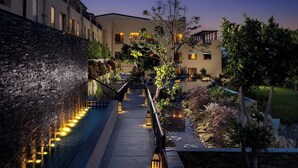 Un hotel moderno con fuente de agua, iluminación exterior y un jardín bien cuidado.