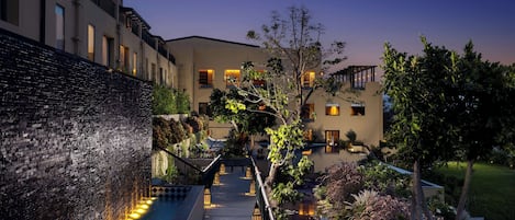 A modern hotel with a water feature, outdoor lighting, and a well-maintained garden.