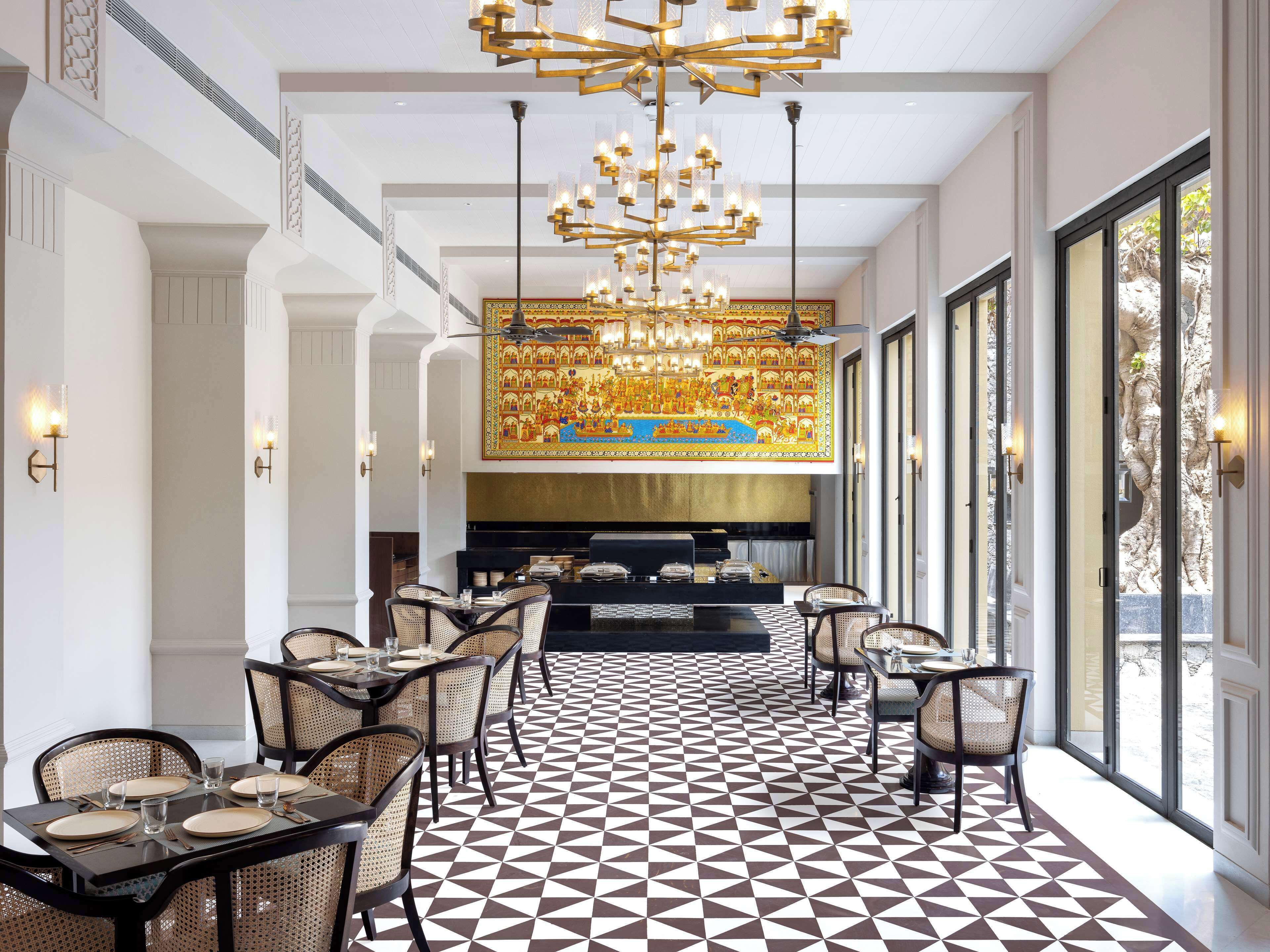 A dining area with geometric patterned flooring, a central chandelier, and a view through large windows.