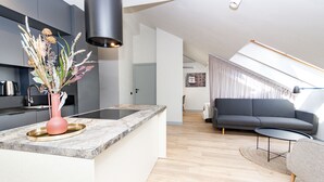 Een moderne keuken met een marmeren aanrecht, een roze vaas met gedroogde bloemen en een inbouwfornuis.