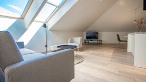 Een modern loft appartement met dakraam, een bank, een salontafel, een televisie en een eethoek.