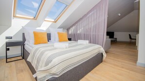 Een moderne slaapkamer met dakraam, een bed met gestreept beddengoed en een houten vloer.