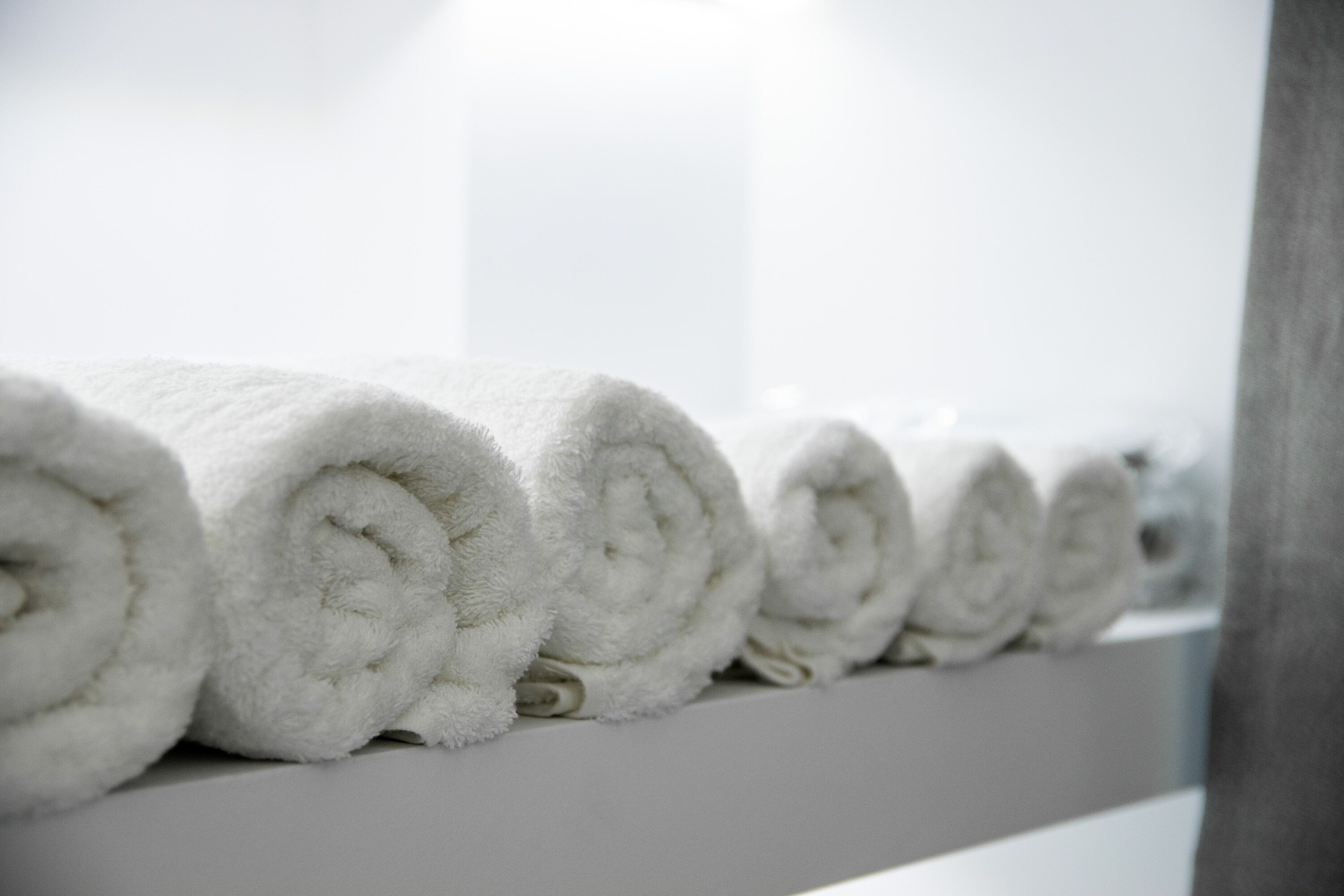 A row of neatly rolled white towels on a white surface.