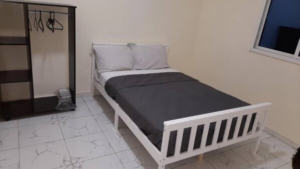 A bedroom with a bed, a wardrobe, and a window.