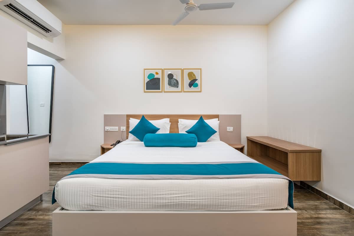 A modern hotel room with a large bed, two bedside tables, a wooden bench, and a ceiling fan.