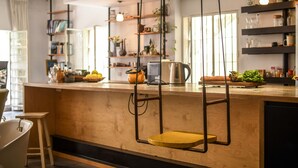 Una cocina moderna con mostradores de madera, sillas colgantes y estantes con utensilios de cocina.