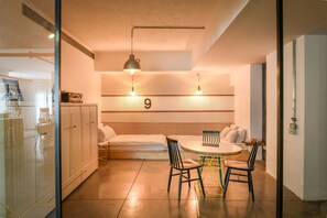 A compact room with a bed, a dining table with chairs, a small kitchenette, and a number '9' on the wall. - Unique and Spacious 2BR Apt with Terrace (Tel Aviv)
