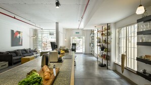 Un interior moderno con área de cocina, una mesa de comedor con comida, un sofá y una estantería.